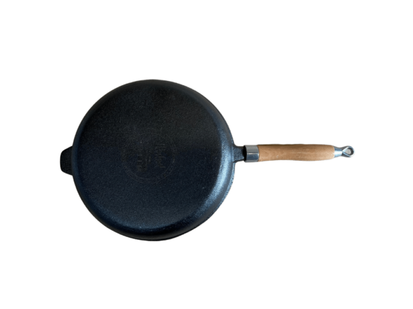 Liatinová panvica s drevenou rukoväťou a vrúbkovaným vnútrom zo zadnej strany